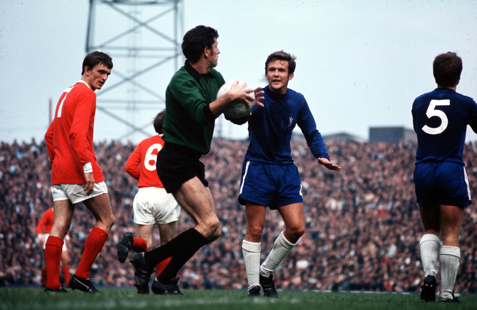 Vintage football match atmosphere with Chelsea players in blue kits and a packed stadium.