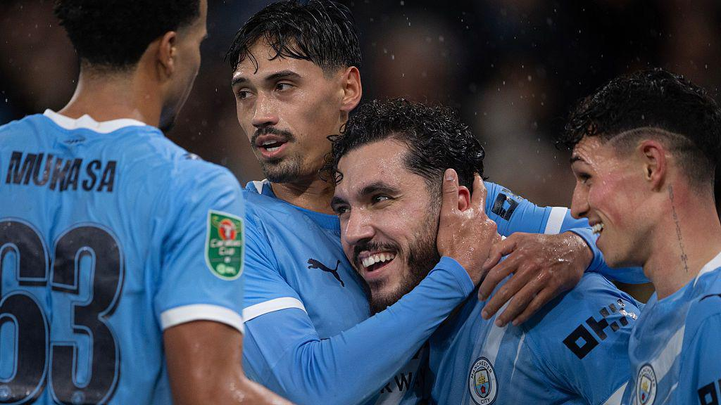 Manchester City players embracing after scoring a goal