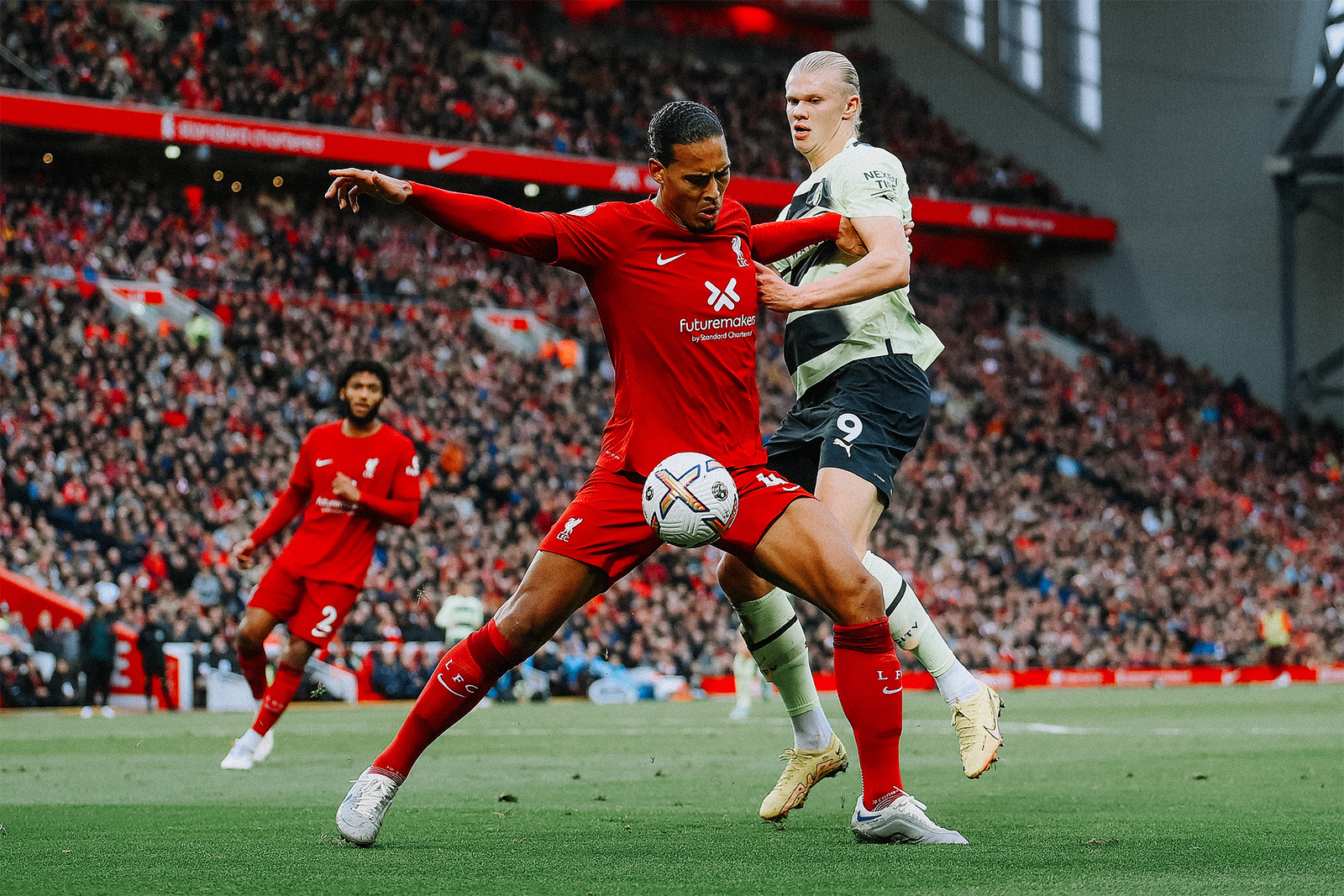 Virgil Van Dijk brushing Erling Haaland off the ball.